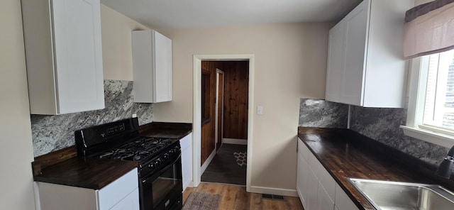 kitchen featuring a sink, a healthy amount of sunlight, black gas range, and wood finished floors