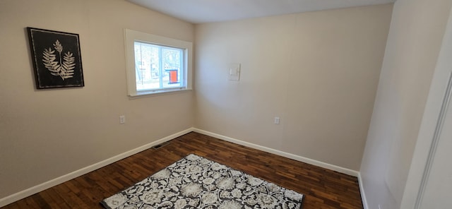 empty room with dark wood-style flooring, baseboards, and visible vents