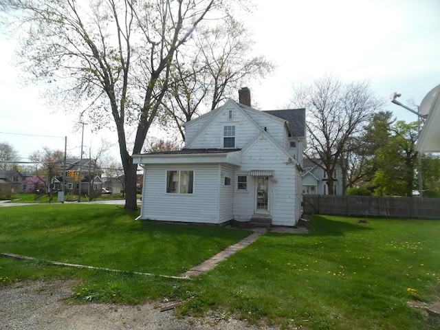 view of front of property with a front lawn, roof with shingles, fence, and a chimney