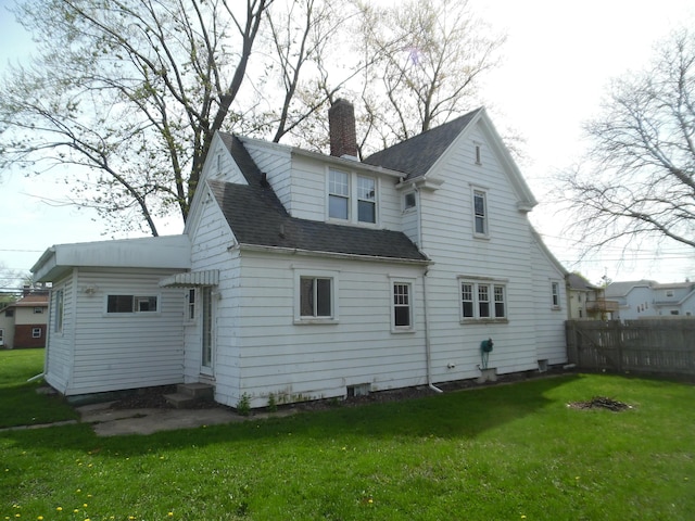 back of property featuring a chimney, roof with shingles, a lawn, fence, and entry steps