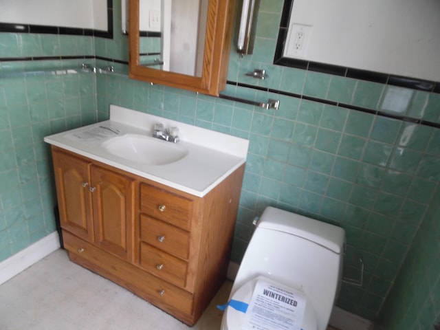 half bathroom with vanity, toilet, and tile walls