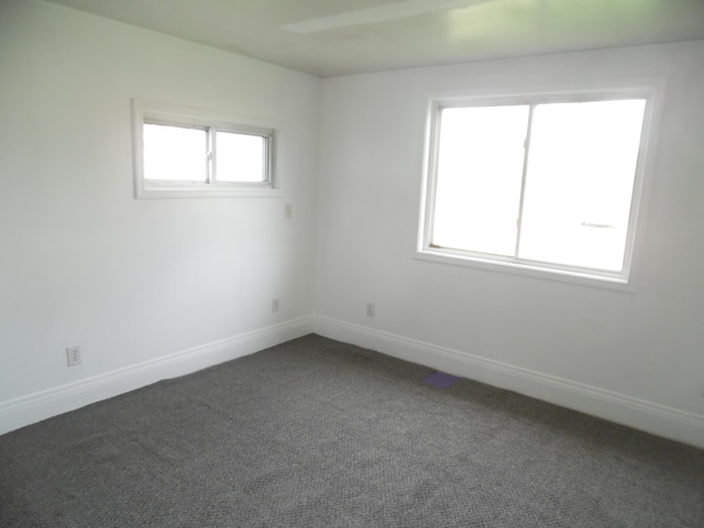 spare room with dark carpet and baseboards