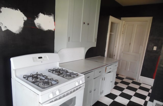 kitchen with light countertops, light floors, white range with gas stovetop, and white cabinetry