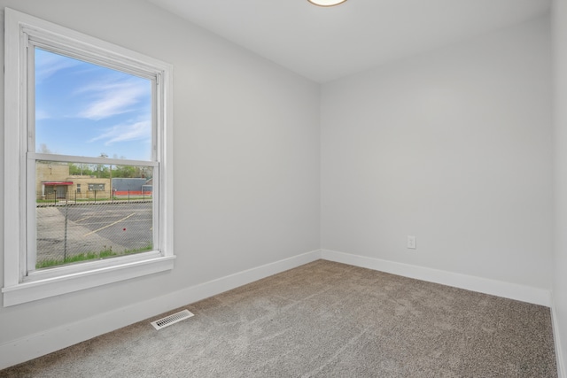 carpeted spare room featuring visible vents and baseboards