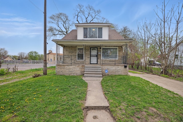 bungalow featuring a porch, fence, and a front lawn