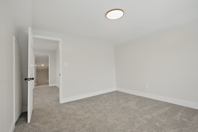 spare room featuring baseboards and light carpet
