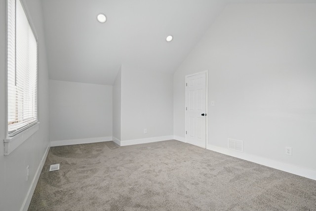 additional living space with carpet flooring, baseboards, vaulted ceiling, and visible vents