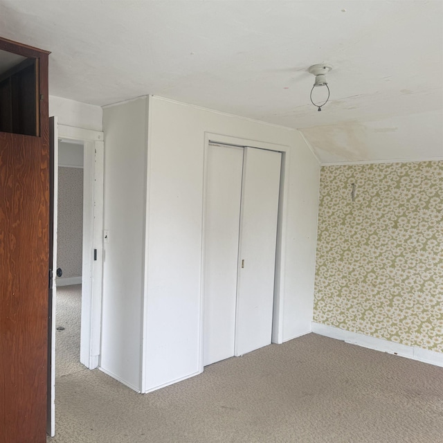 unfurnished bedroom featuring carpet floors, wallpapered walls, baseboards, and a closet