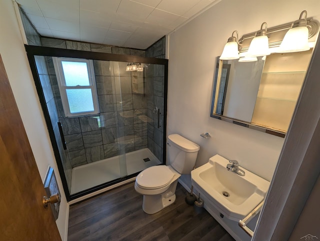 bathroom featuring wood finished floors, a sink, a stall shower, and toilet