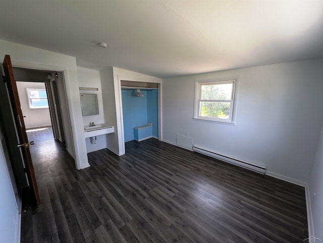 unfurnished bedroom featuring dark wood-style flooring, baseboards, baseboard heating, and a closet