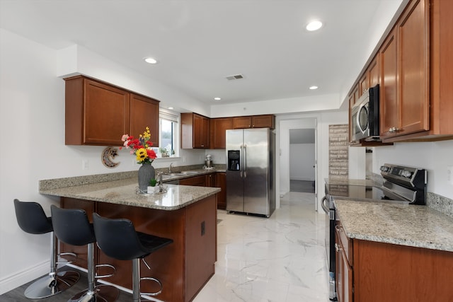 kitchen with visible vents, appliances with stainless steel finishes, a sink, light stone counters, and a peninsula