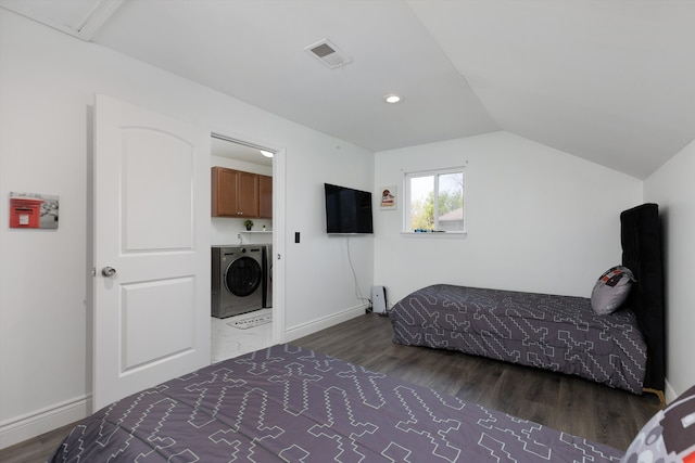 bedroom with baseboards, visible vents, wood finished floors, and washer and dryer