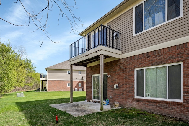 back of property featuring a balcony, a yard, a patio area, and brick siding
