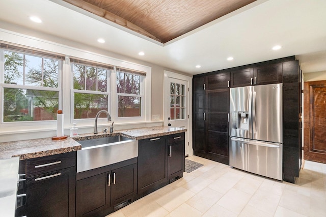 kitchen featuring light stone counters, a sink, recessed lighting, and stainless steel fridge with ice dispenser