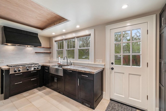 kitchen with wall chimney range hood, recessed lighting, light stone countertops, and stainless steel gas cooktop