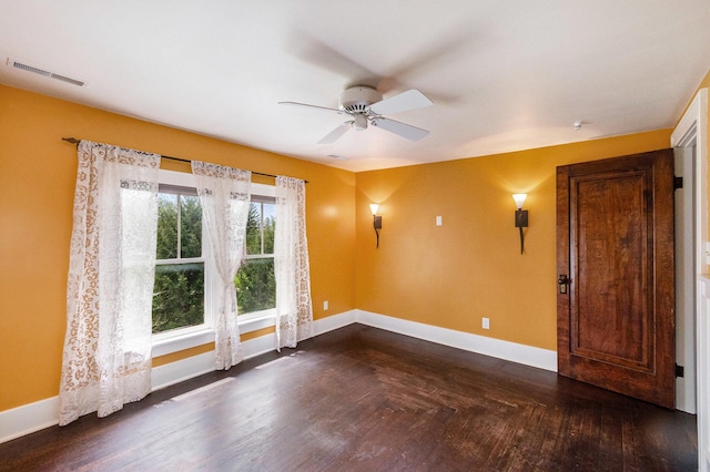 empty room featuring baseboards, ceiling fan, dark wood-style flooring, and visible vents