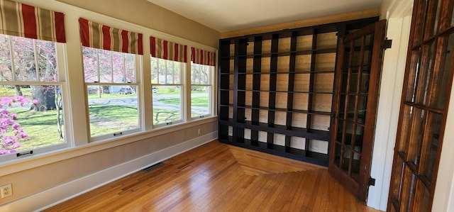 spare room with visible vents, baseboards, and wood finished floors