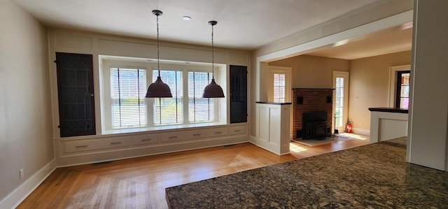 unfurnished dining area featuring baseboards, visible vents, wood finished floors, and a wood stove