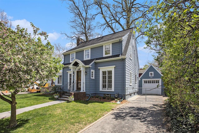 906 Granger Ave, Ann Arbor, MI 48104 - view of front facade with a front lawn, aphalt driveway, a garage, an outbuilding, and a chimney