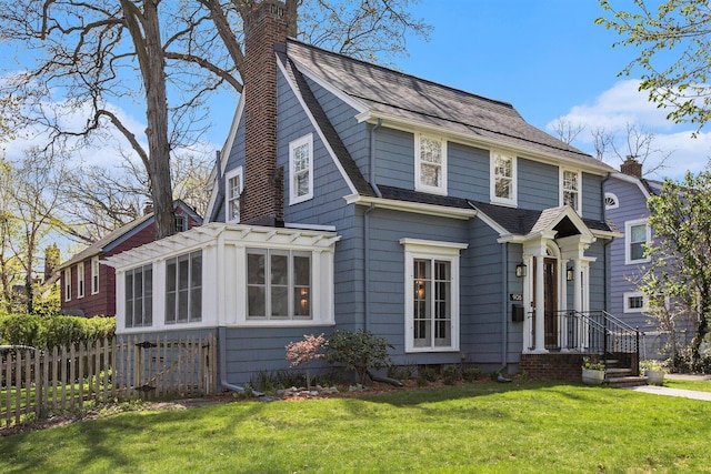 906 Granger Ave, Ann Arbor, MI 48104 - view of front of house featuring a chimney, a front yard, a sunroom, fence, and a shingled roof