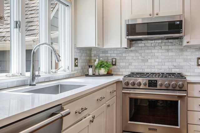 906 Granger Ave, Ann Arbor, MI 48104 - kitchen featuring light countertops, stainless steel appliances, decorative backsplash, and a sink