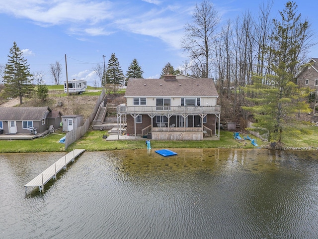 back of house featuring stairway, a deck with water view, and a lawn