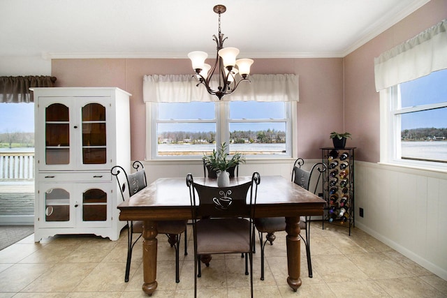 dining room featuring a chandelier, crown molding, wainscoting, and light tile patterned floors