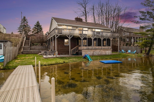 rear view of house featuring stairway, a chimney, a deck with water view, and a patio