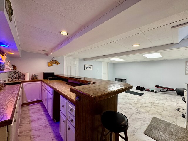 2361 Montroyal Ave, Waterford, MI 48328 - kitchen with wood counters, a kitchen breakfast bar, a drop ceiling, and a peninsula