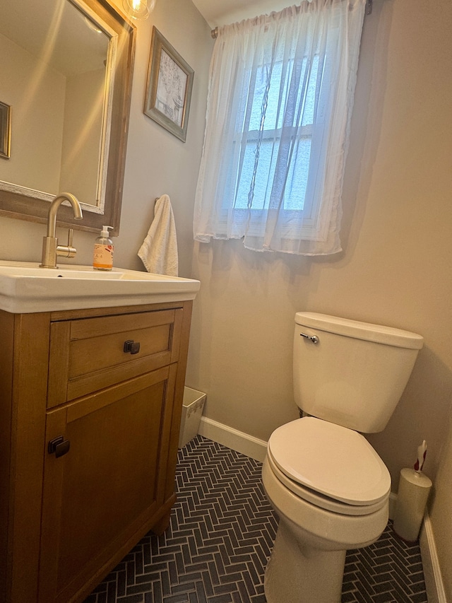 half bathroom featuring baseboards, vanity, and toilet