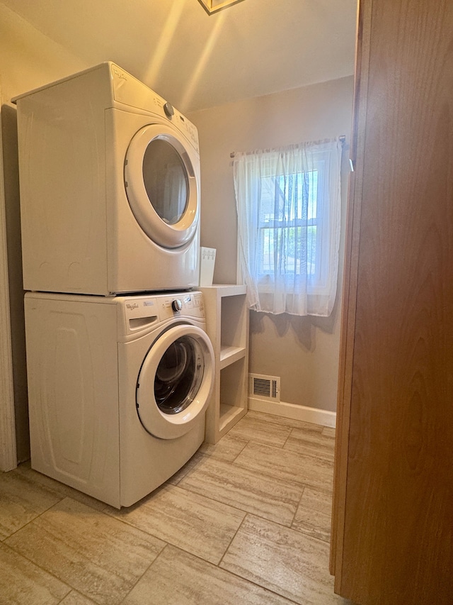 washroom featuring visible vents, stacked washer and dryer, baseboards, and laundry area