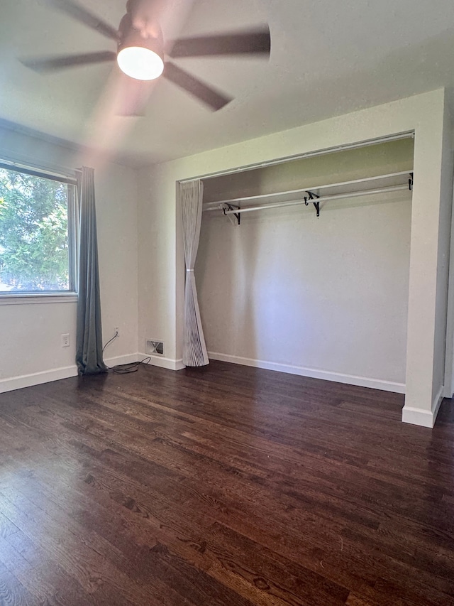 unfurnished bedroom featuring baseboards, ceiling fan, dark wood-style floors, and a closet