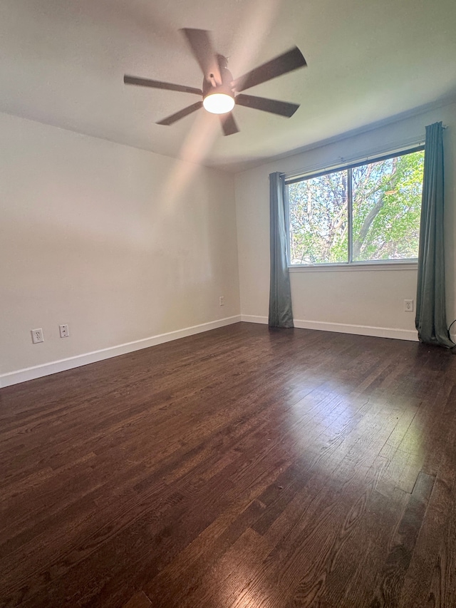 spare room featuring baseboards, ceiling fan, and dark wood-style floors