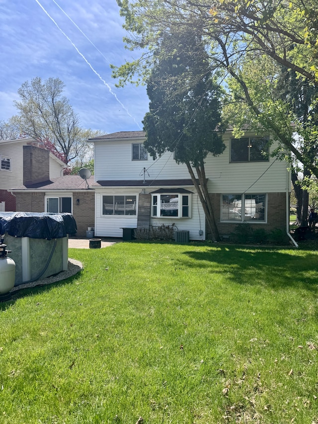 back of property with a lawn and central AC