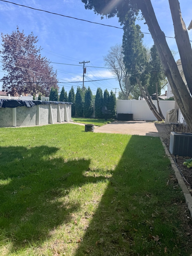 view of yard featuring a patio, central AC unit, fence, and a covered pool