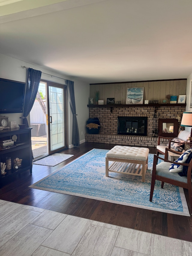 living area with a brick fireplace, baseboards, and wood finished floors