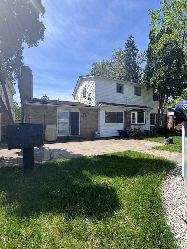 view of front of property featuring brick siding, a front lawn, and a patio area