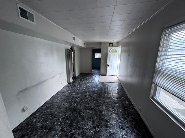hall featuring baseboards, visible vents, and a healthy amount of sunlight