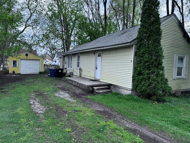 rear view of house with a detached garage, a yard, and an outdoor structure