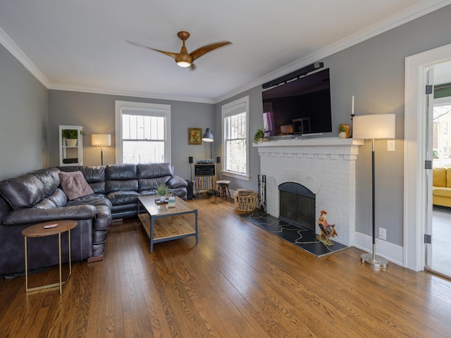 living room with crown molding, ceiling fan, a fireplace, baseboards, and wood finished floors