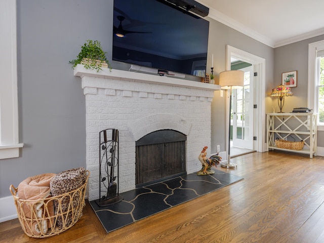 interior details with crown molding, baseboards, a brick fireplace, and wood finished floors