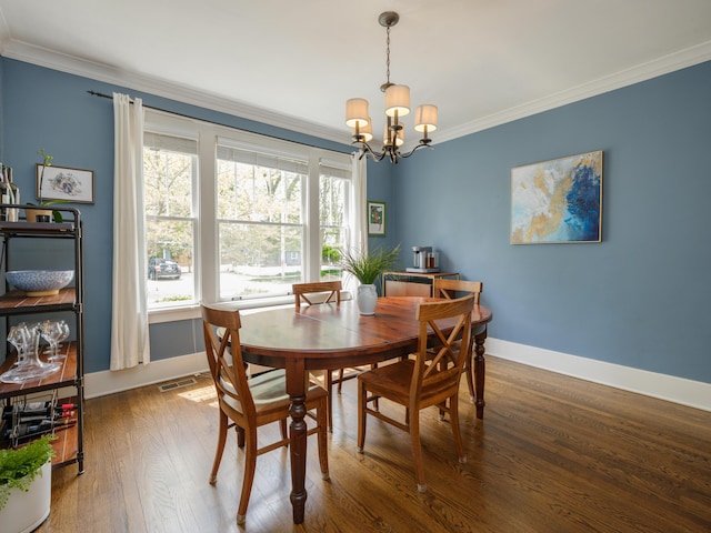 dining space with visible vents, wood finished floors, baseboards, an inviting chandelier, and ornamental molding