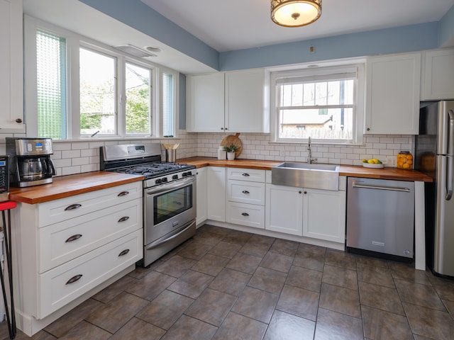 kitchen featuring appliances with stainless steel finishes, wooden counters, a sink, and a healthy amount of sunlight