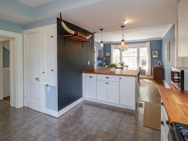 kitchen featuring butcher block countertops, open shelves, a chandelier, and white cabinets