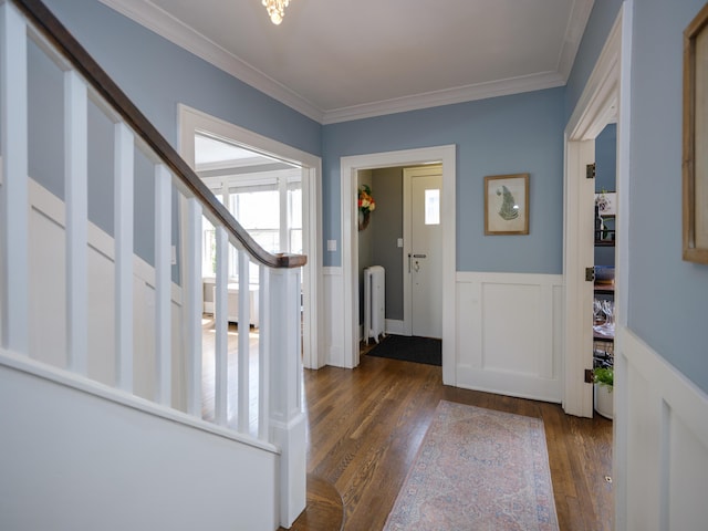entrance foyer featuring radiator, a wainscoted wall, wood finished floors, ornamental molding, and stairway