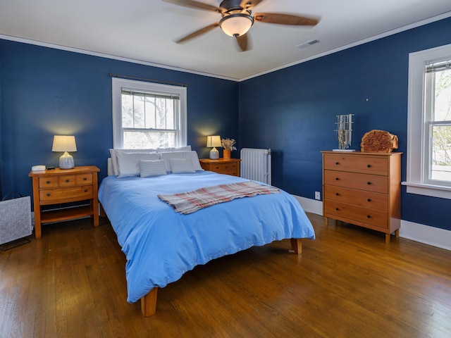 bedroom featuring radiator heating unit, ornamental molding, wood finished floors, and visible vents