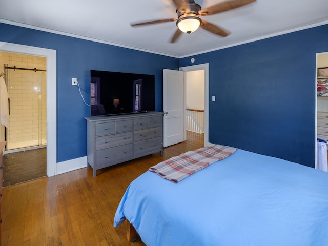 bedroom with ornamental molding, wood finished floors, baseboards, ceiling fan, and a barn door