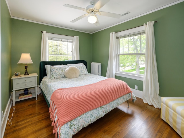 bedroom featuring radiator heating unit, a ceiling fan, baseboards, wood finished floors, and ornamental molding