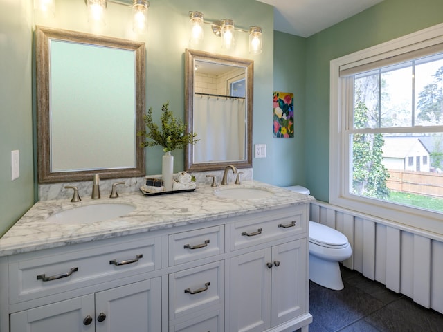 full bathroom with double vanity, toilet, and a sink