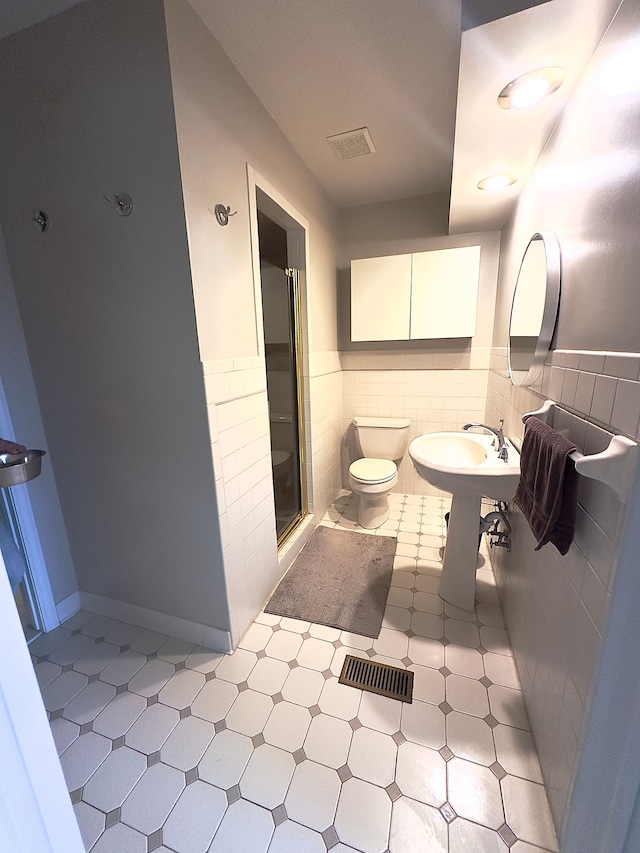 full bathroom featuring tile walls, a stall shower, toilet, and visible vents